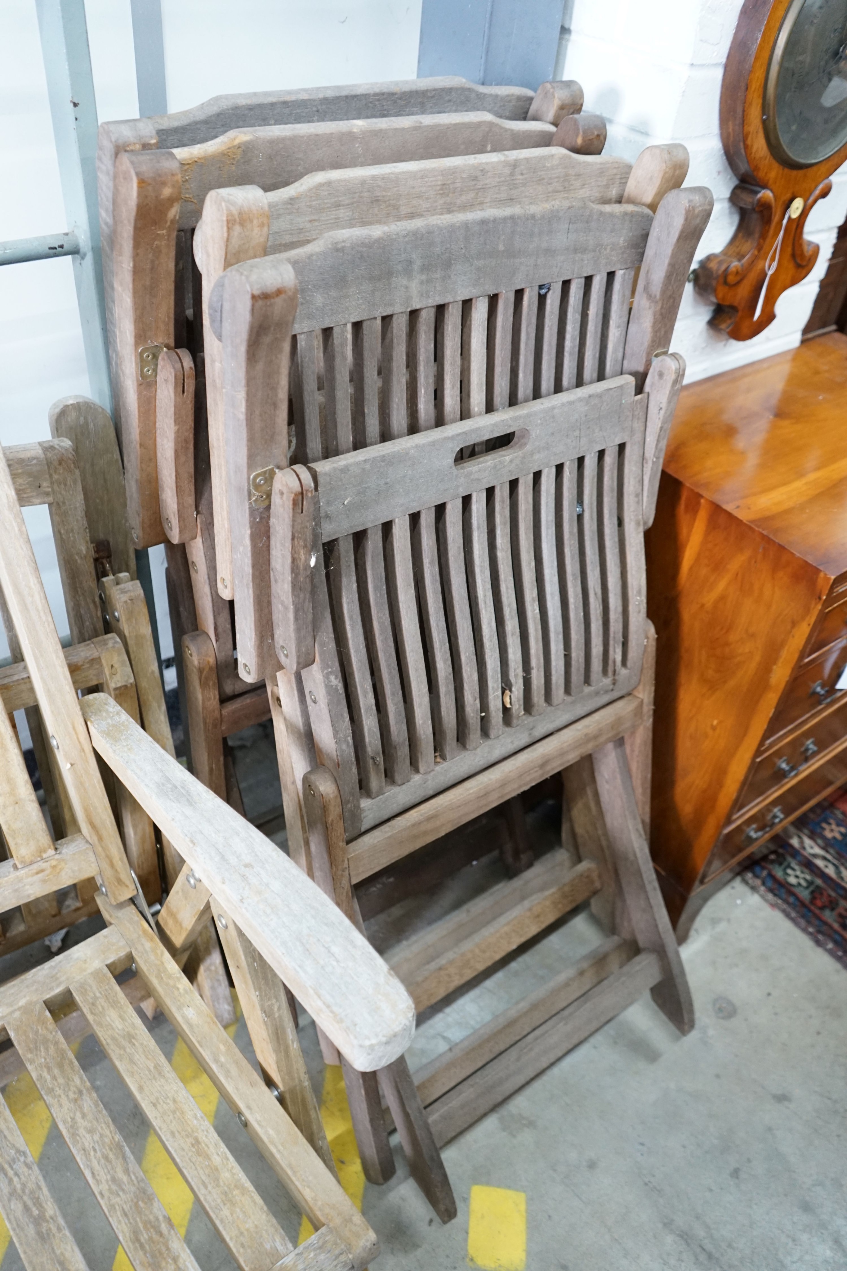 Four weathered teak folding garden chairs, a pair of teak reclining elbow chairs and a pair of Aristo garden oil lamps